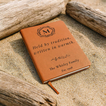 Brown leather notebook with engraved text on a sandy background