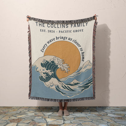 Person holding a blanket with a wave design and text, featuring 'The Collins Family' and a quote.