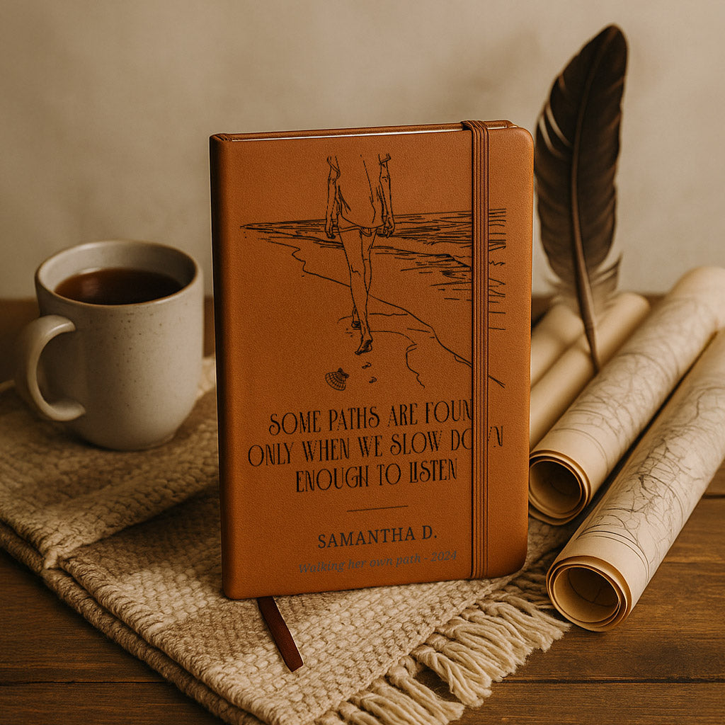 Brown leather notebook with engraved text and a cup of coffee on a wooden surface