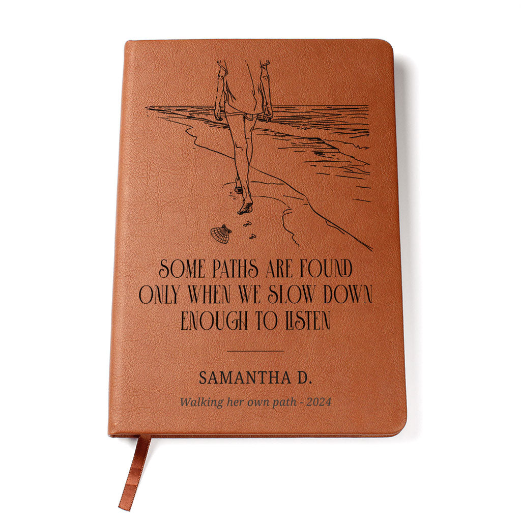Brown leather notebook with engraved design and text on a white background