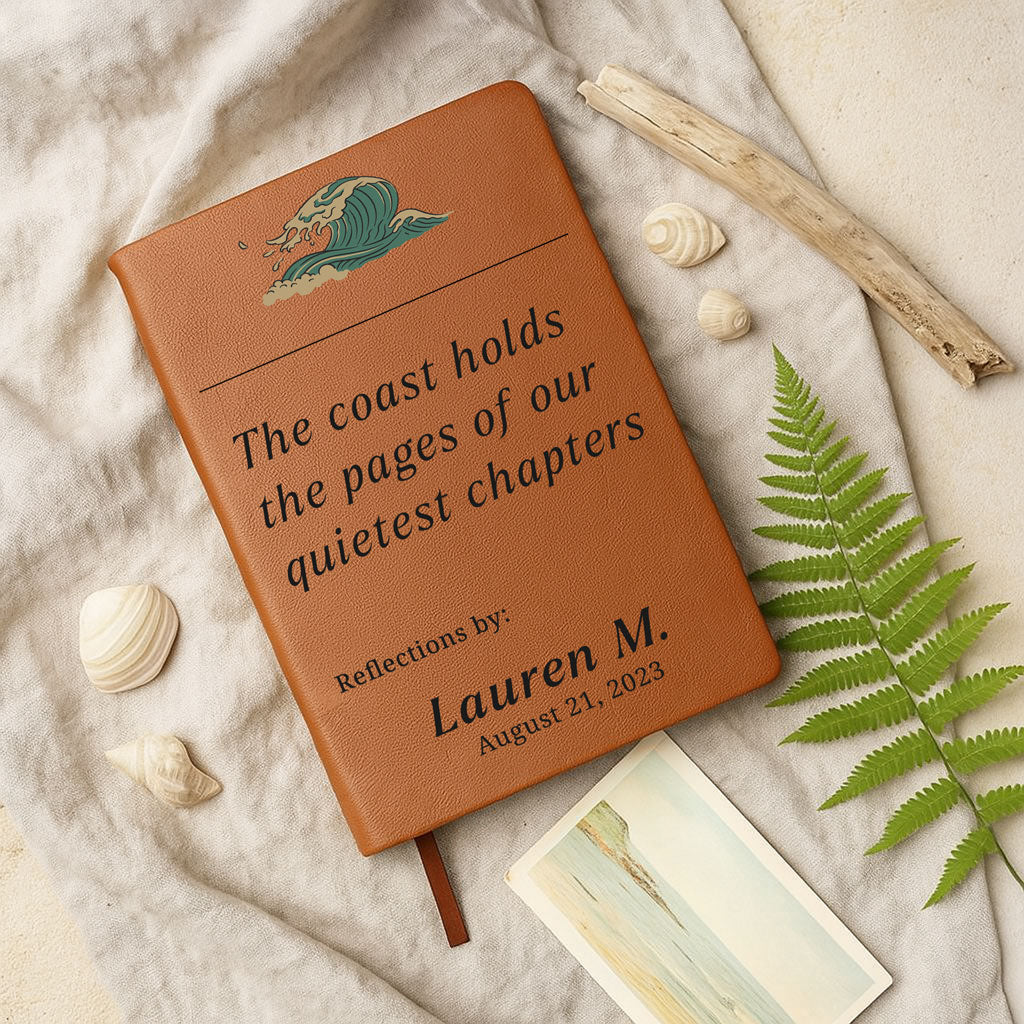 Brown leather notebook with engraved text on a sandy background with shells and ferns