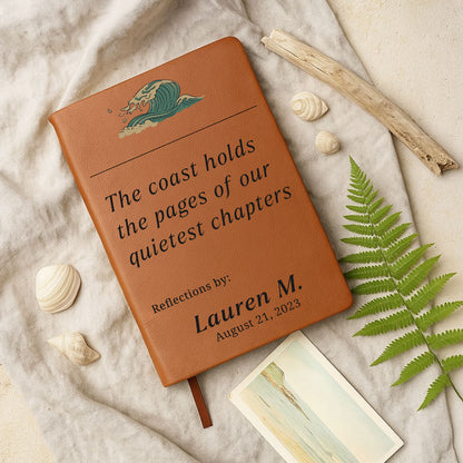 Brown leather notebook with engraved text on a sandy background with shells and ferns